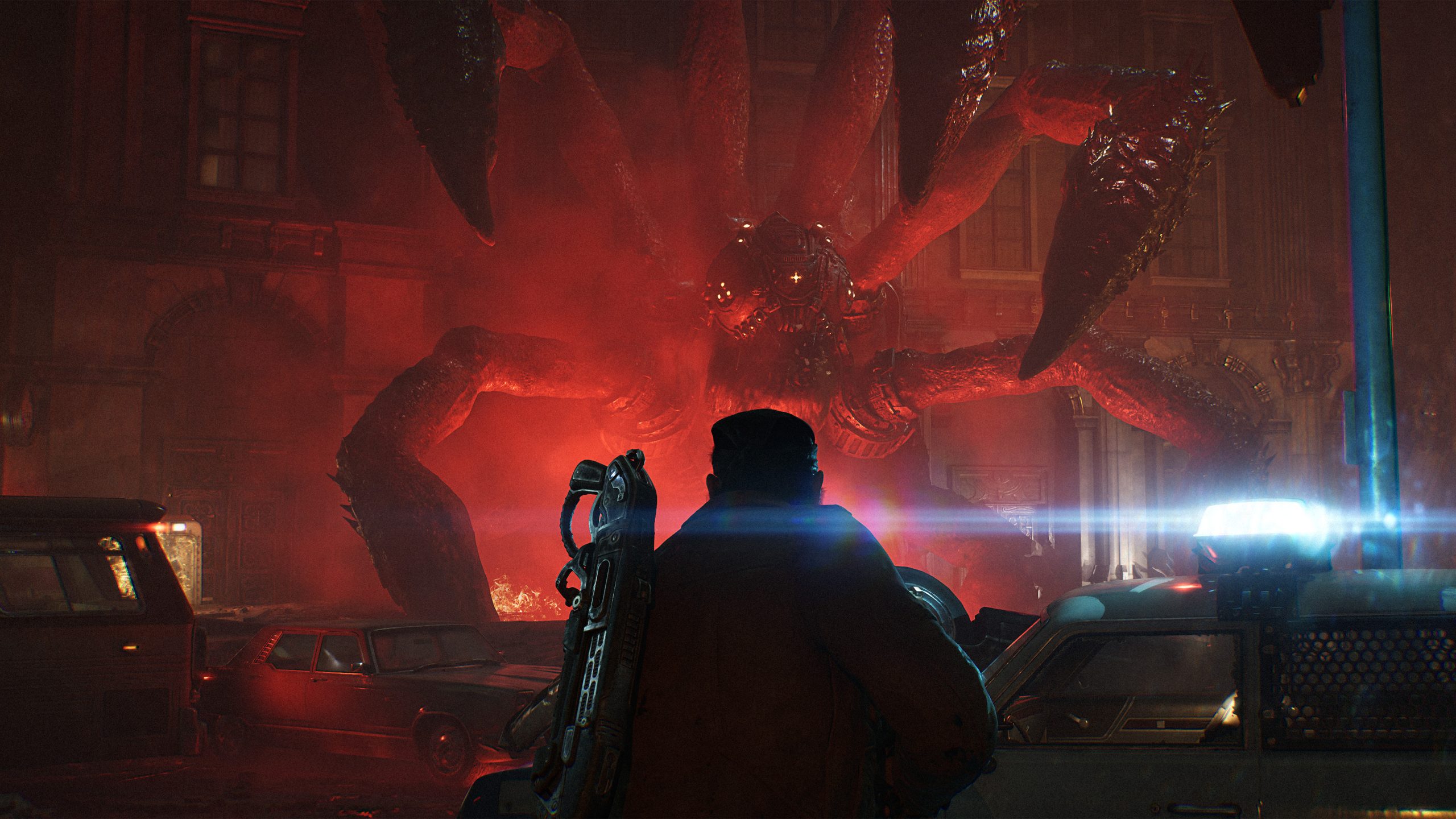 A soldier with a Lancer rifle faces a towering Locust creature rising over a burning city street on Emergence Day.